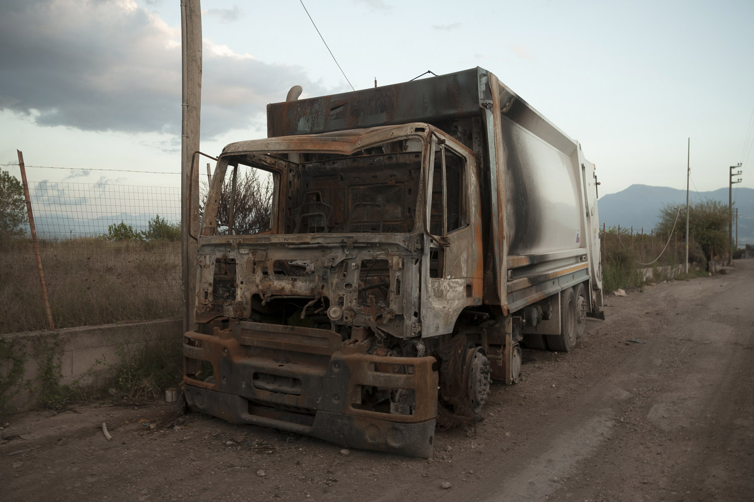 A burned out garbage trucks on the road to Cava Sari. While the peaceful protests were completely ignored, a string of fire attacks against garbage trucks by small groups of masked protesters captured the attention of the media.